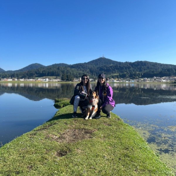 Dos chicas senderistas posando con su perros en un lago