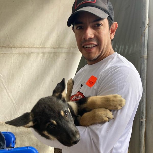 Hombre feliz cargando a un cachorro negro con café