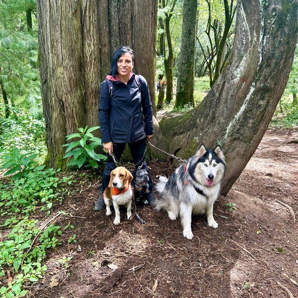 Mujer feliz con sus perros en el bosque