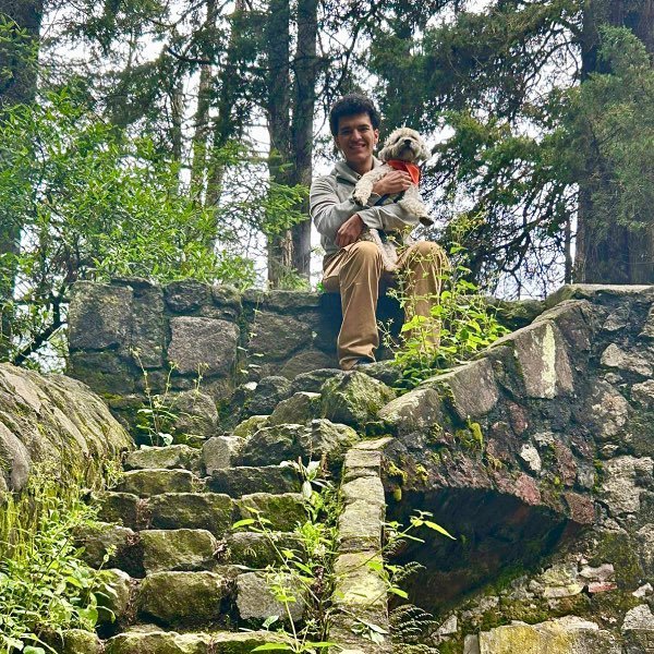 Hombre feliz con sus perro en las escaleras de una ruina en el bosque