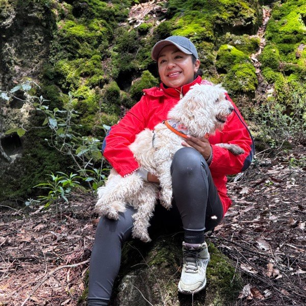 Mujer feliz cargando a su perro blanco en el bosque