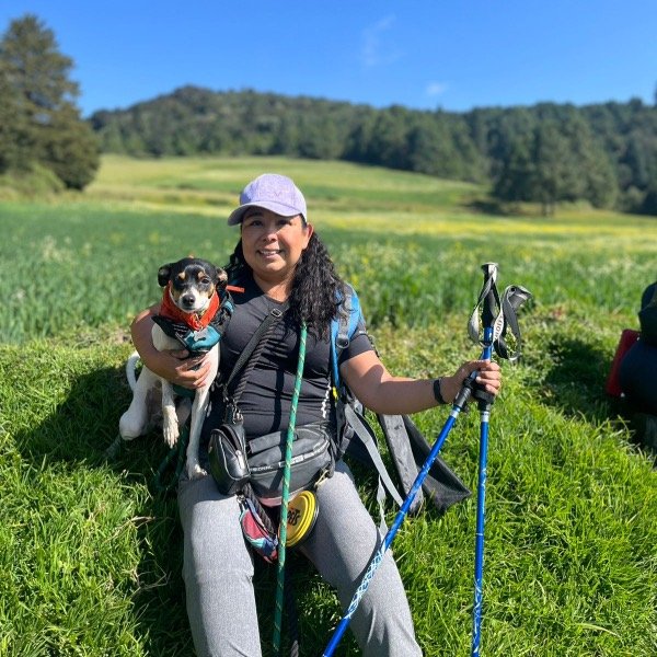 Mujer senderista feliz sentada en el pasto con su perro